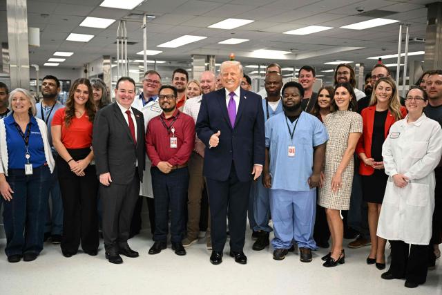 US President Donald Trump poses for a photo with employees as he tours Thermo Fisher Scientific laboratories in Cincinnati, Ohio, on March 11, 2026. Trump is meeting with Thermo Fisher officials to discuss prescription drug prices. (Photo by Jim WATSON / AFP)