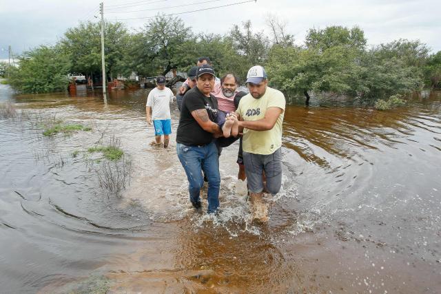 People rescue a man during a flood in Agua Azul, Tucuman province, Argentina on March 11, 2026. (Photo by Walter MONTEROS / AFP)