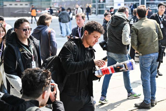 McLaren's British driver Lando Norris signs autographs for the fans in the paddock at the Shanghai International Circuit ahead of the Formula One Chinese Grand Prix in Shanghai on March 12, 2026. (Photo by Hector RETAMAL / AFP)