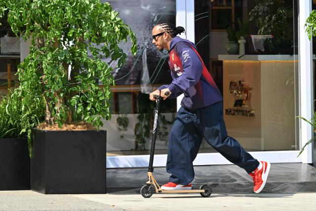 Ferrari's British driver Lewis Hamilton rides a scooter in the paddock at the Shanghai International Circuit ahead of the Formula One Chinese Grand Prix in Shanghai on March 12, 2026. (Photo by Hector RETAMAL / AFP)