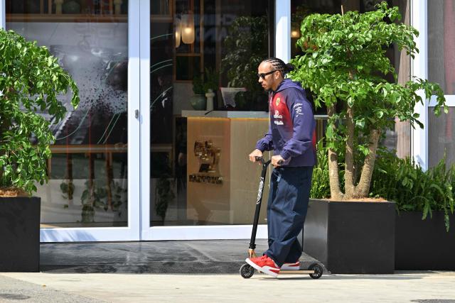 Ferrari's British driver Lewis Hamilton rides a scooter in the paddock at the Shanghai International Circuit ahead of the Formula One Chinese Grand Prix in Shanghai on March 12, 2026. (Photo by Hector RETAMAL / AFP)