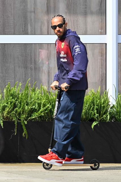 Ferrari's British driver Lewis Hamilton rides a scooter in the paddock at the Shanghai International Circuit ahead of the Formula One Chinese Grand Prix in Shanghai on March 12, 2026. (Photo by Hector RETAMAL / AFP)