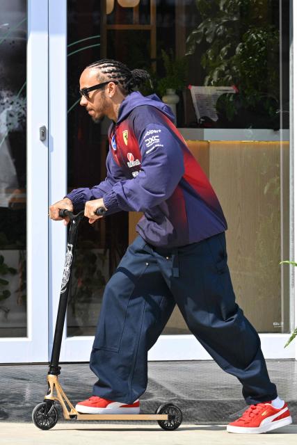 Ferrari's British driver Lewis Hamilton rides a scooter in the paddock at the Shanghai International Circuit ahead of the Formula One Chinese Grand Prix in Shanghai on March 12, 2026. (Photo by Hector RETAMAL / AFP)