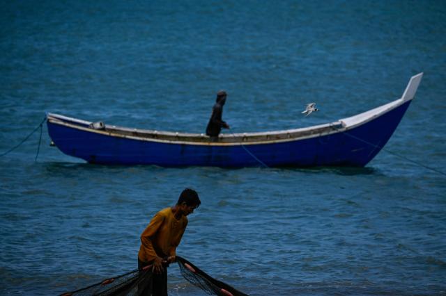 A fisherman pulls a net for cleaning at a beach in Banda Aceh on March 12, 2026. (Photo by CHAIDEER MAHYUDDIN / AFP)