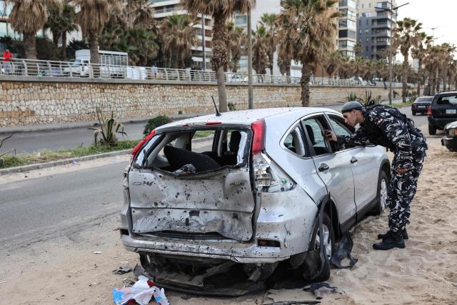 A policeman inspects a damaged car at the site of an Israeli airstrike on the seaside area of Ramlet al-Bayda in Beirut early on March 12, 2026. Lebanon said an Israeli strike on central Beirut's seafront killed at least seven people early on March 12, another attack in the heart of the capital as Iran-backed Hezbollah launched more missiles at Israel. (Photo by Anwar AMRO / AFP)