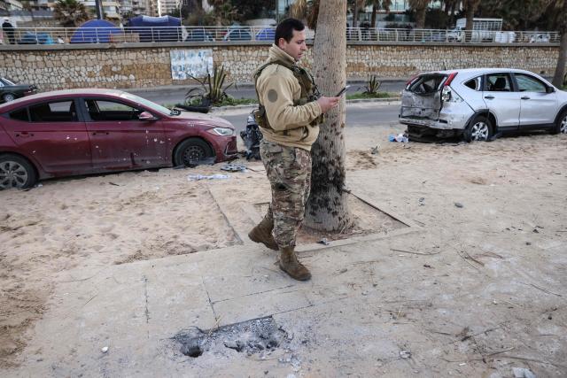 A soldier inspects the site of an Israeli airstrike on the seaside area of Ramlet al-Bayda in Beirut, with tents sheltering displaced people visible in the background, on March 12, 2026. Lebanon said an Israeli strike on central Beirut's seafront killed at least seven people early on March 12, another attack in the heart of the capital as Iran-backed Hezbollah launched more missiles at Israel. (Photo by Anwar AMRO / AFP)