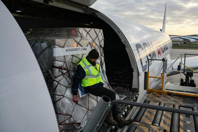 Workers load humanitarian aid into an aircraft destined for Lebanon at Roissy-Charles de Gaulle Airport on the outskirts of Paris on March 12, 2026. France is preparing to triple its humanitarian support to Lebanon by sending 60 tons of aid on March 12, 2026 for refugees leaving the south of the country, where Israel is conducting military operations against the pro-Iranian Hezbollah, the French foreign minister announced on March 11, 2026. (Photo by Dimitar DILKOFF / AFP)