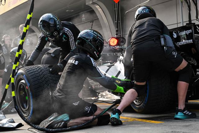 Mercedes team members practice a pit stop with the car of Mercedes' British driver George Russell ahead of the Formula One Chinese Grand Prix at the Shanghai International Circuit in Shanghai on March 12, 2026. (Photo by Hector RETAMAL / AFP)