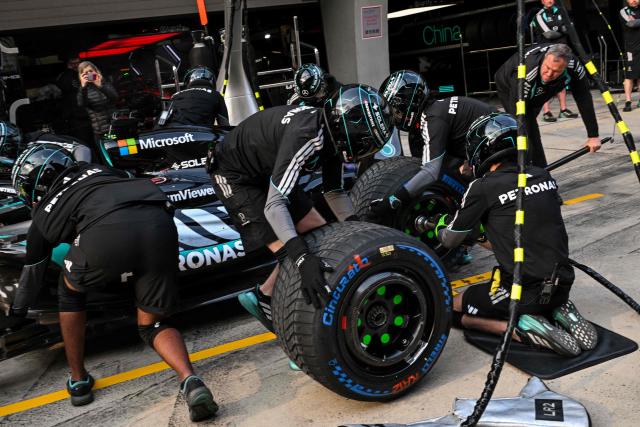 Mercedes team members practice a pit stop with the car of Mercedes' British driver George Russell ahead of the Formula One Chinese Grand Prix at the Shanghai International Circuit in Shanghai on March 12, 2026. (Photo by Hector RETAMAL / AFP)