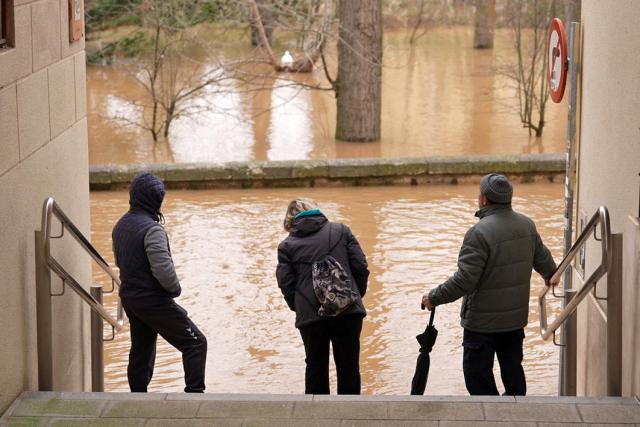 (FILES) People observe floodwaters covering a street after the Douro River overflowed in Aranda de Duero, Burgos province, in northern Spain, on February 15, 2026. Spain saw its highest rainfall levels for January and February in almost fifty years. These storms resulted in several fatalities and the displacement of an entire town, according to a report released on March 12, 2026 by the state meteorological agency, Aemet (Photo by CESAR MANSO / AFP)