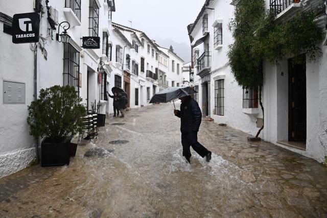 (FILES) A man crosses a flooded street in Grazalema, southern Spain, on February 5, 2026, amid Storm Leonardo. Spain saw its highest rainfall levels for January and February in almost fifty years. These storms resulted in several fatalities and the displacement of an entire town, according to a report released on March 12, 2026 by the state meteorological agency, Aemet (Photo by JORGE GUERRERO / AFP)