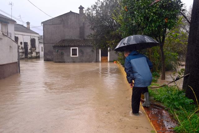 (FILES) A man crosses a flooded street in Jimera de Libar, southern Spain, on February 4, 2026 amid Storm Leonardo. Spain saw its highest rainfall levels for January and February in almost fifty years. These storms resulted in several fatalities and the displacement of an entire town, according to a report released on March 12, 2026 by the state meteorological agency, Aemet (Photo by JORGE GUERRERO / AFP)