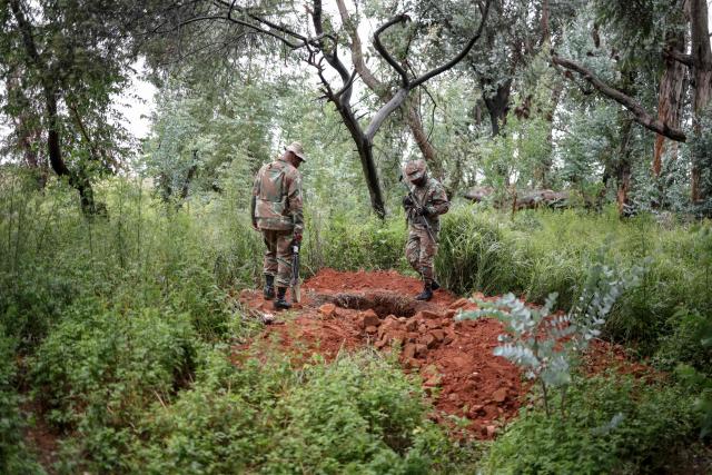 Soldiers of the South African National Defence Force (SANDF) destroy bags of soil inspect a hole in the ground used by artisanal miners, during a patrol in Randfontein on MArch 12, 2026. South Africa deployed soldiers for a year to provinces struggling to quell rampant crime and illegal mining, according to a mission plan presented to parliament on March 4, 2026.
President Cyril Ramaphosa announced the deployment last month, calling organised crime the "most immediate threat" to South Africa's democracy and economic development. (Photo by EMMANUEL CROSET / AFP)