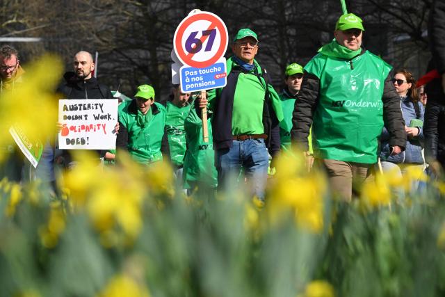 A protester holds a sign reading "Hands off our pensions" during a demonstration during a national day of action against the austerity plan of the federal Arizona government, in Brussels on March 12, 2026. Belgium will be running at a slower pace on March 12, 2026 due to a call for a strike by the country’s three main trade unions, resulting in the suspension of all traffic at Charleroi Airport and the cancellation of departing flights from Brussels-Zaventem. (Photo by Nicolas TUCAT / AFP)
