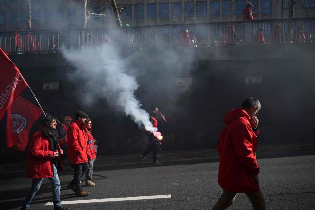 Protesters hold flags as they take part in a demonstration during a national day of action against the austerity plan of the federal Arizona government, in Brussels on March 12, 2026. Belgium will be running at a slower pace on March 12, 2026 due to a call for a strike by the country’s three main trade unions, resulting in the suspension of all traffic at Charleroi Airport and the cancellation of departing flights from Brussels-Zaventem. (Photo by Nicolas TUCAT / AFP)