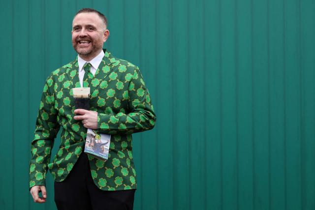 A racegoer drinks a pint of Guinness to mark 'St Patrick's Thursday' with an Irish them, on the third day of the Cheltenham Festival at Cheltenham Racecourse, in Cheltenham, western England on March 12, 2026. (Photo by Adrian Dennis / AFP)