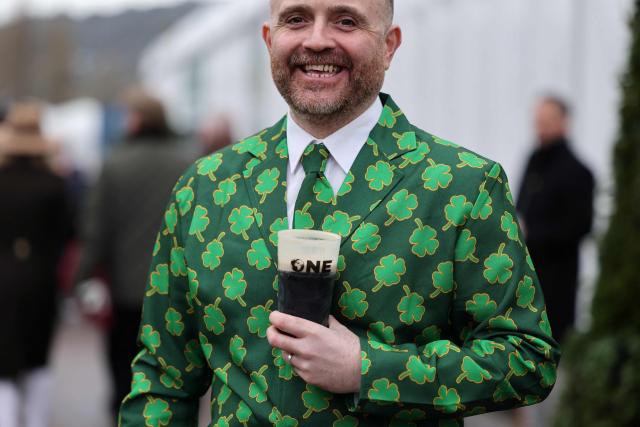A racegoer drinks a pint of Guinness to mark 'St Patrick's Thursday' with an Irish them, on the third day of the Cheltenham Festival at Cheltenham Racecourse, in Cheltenham, western England on March 12, 2026. (Photo by Adrian Dennis / AFP)