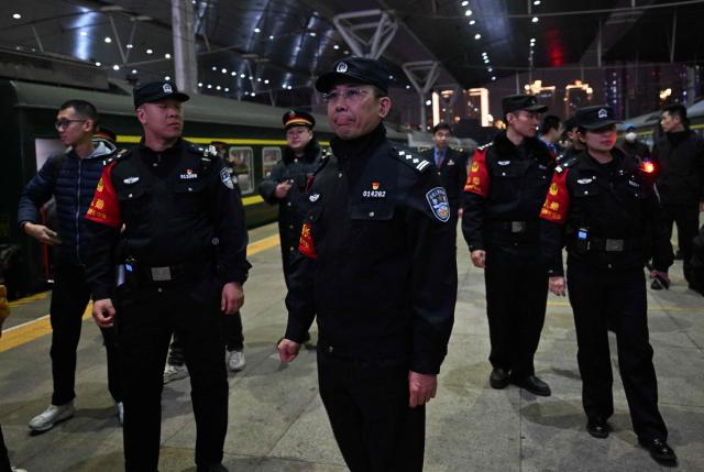 Police stand guard on the platform as people try to take pictures of the K27 train bound to Pyongyang, at the Tianjin station in Tianjin on March 12, 2026. A passenger train that departed from the northeastern Chinese city of Dandong arrived in the North Korean capital Pyongyang on March 12, as rail service between the neighbouring countries resumed after six years. (Photo by ADEK BERRY / AFP)