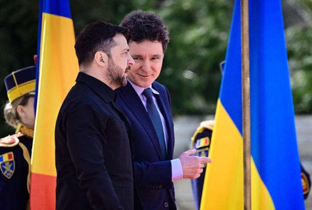 Romanian President Nicusor Dan (R) speaks with his Ukrainian counterpart Volodymyr Zelensky during an official welcoming ceremony at Cotroceni Palace, the official residence of the Romanian president, in Bucharest on March 12, 2026. Ukrainian President Zelensky arrived on March 12 in Romania, where he was to visit an F-16 fighter jet training centre and meet Romania's leader, before visiting France later this week. The visits come at a time of uncertainty over planned peace talks between Kyiv and Moscow that have been spearheaded by the United States and derailed by the US-Israeli war with Iran. (Photo by Daniel MIHAILESCU / AFP)