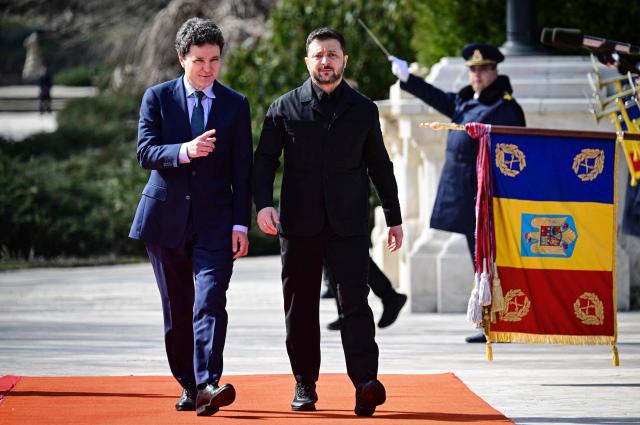 Romanian President Nicusor Dan (L) welcomes his Ukrainian counterpart Volodymyr Zelensky during an official welcoming ceremony at Cotroceni Palace, the official residence of the Romanian president, in Bucharest on March 12, 2026. Ukrainian President Zelensky arrived on March 12 in Romania, where he was to visit an F-16 fighter jet training centre and meet Romania's leader, before visiting France later this week. The visits come at a time of uncertainty over planned peace talks between Kyiv and Moscow that have been spearheaded by the United States and derailed by the US-Israeli war with Iran. (Photo by Daniel MIHAILESCU / AFP)