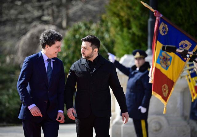 Romanian President Nicusor Dan (L) welcomes his Ukrainian counterpart Volodymyr Zelensky during an official welcoming ceremony at Cotroceni Palace, the official residence of the Romanian president, in Bucharest on March 12, 2026. Ukrainian President Zelensky arrived on March 12 in Romania, where he was to visit an F-16 fighter jet training centre and meet Romania's leader, before visiting France later this week. The visits come at a time of uncertainty over planned peace talks between Kyiv and Moscow that have been spearheaded by the United States and derailed by the US-Israeli war with Iran. (Photo by Daniel MIHAILESCU / AFP)