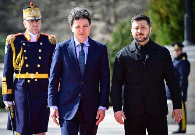 Romanian President Nicusor Dan (L) welcomes his Ukrainian counterpart Volodymyr Zelensky during an official welcoming ceremony at Cotroceni Palace, the official residence of the Romanian president, in Bucharest on March 12, 2026. Ukrainian President Zelensky arrived on March 12 in Romania, where he was to visit an F-16 fighter jet training centre and meet Romania's leader, before visiting France later this week. The visits come at a time of uncertainty over planned peace talks between Kyiv and Moscow that have been spearheaded by the United States and derailed by the US-Israeli war with Iran. (Photo by Daniel MIHAILESCU / AFP)