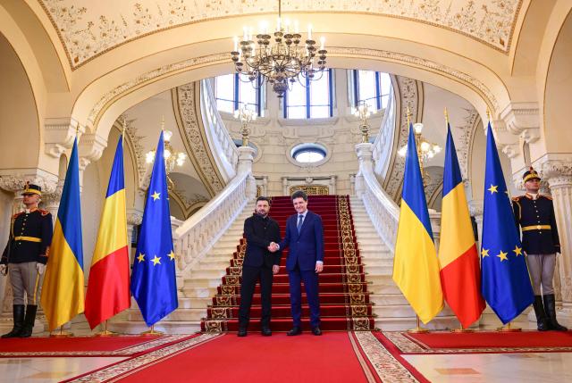 Romanian President Nicusor Dan (R) welcomes his Ukrainian counterpart Volodymyr Zelensky during an official welcoming ceremony at Cotroceni Palace, the official residence of the Romanian president, in Bucharest on March 12, 2026. Ukrainian President Zelensky arrived on March 12 in Romania, where he was to visit an F-16 fighter jet training centre and meet Romania's leader, before visiting France later this week. The visits come at a time of uncertainty over planned peace talks between Kyiv and Moscow that have been spearheaded by the United States and derailed by the US-Israeli war with Iran. (Photo by Daniel MIHAILESCU / AFP)