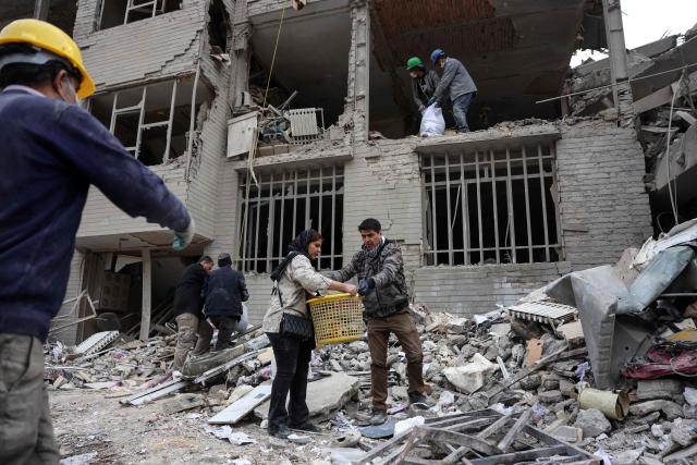 Iranians collect belongings from the rubble of a damaged residential building in Tehran on March 12, 2026. The United States and Israel started striking Iran on February 28, killing the Iranian supreme leader and top military leaders, and prompting authorities to retaliate with strikes on Israel and across the Gulf. (Photo by AFP) / 