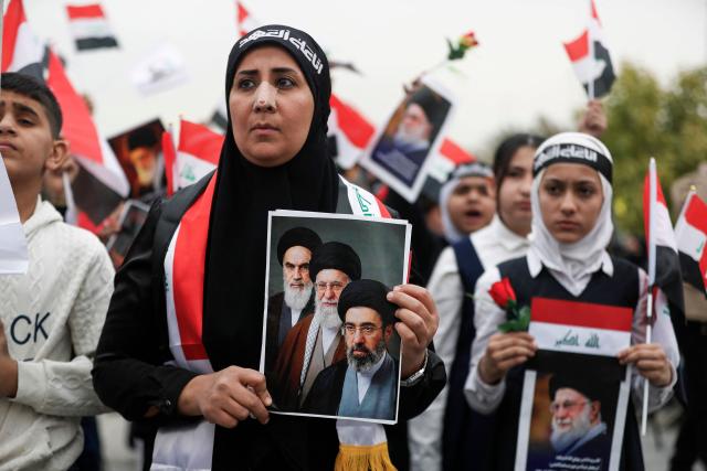 A teacher joins schoolchildren in an anti-US and Israeli demonstration in Baghdad on March 12, 2026. Air strikes killed at least nine Iran-backed fighters in Iraq on March 12 near the Iraqi-Syrian border, two senior security officials told AFP. The Middle East war, which was triggered on February 28 by American-Israeli attacks on Iran, is hampering the global economy's supply of oil and weakening production capacity. (Photo by AHMAD AL-RUBAYE / AFP)
