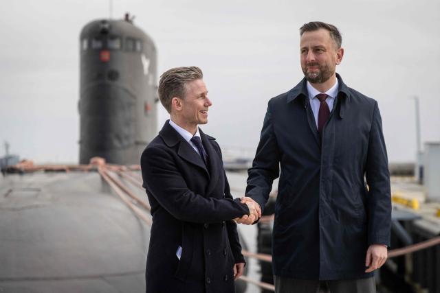 Poland's Deputy Prime Minister and Defence Minister Wladyslaw Kosiniak-Kamysz (R) and Sweden's Defence Minister Pal Jonson (L) shake hands after a joint press conference in front of Polish Navy warship ORP Orzel, a 40-year-old Soviet era made Kilo-class submarine which is the last operating submarine in the Polish Navy, at the Polish Navy base in Gdynia on March 12, 2026. (Photo by Wojtek RADWANSKI / AFP)