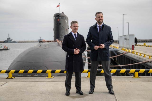 Poland's Deputy Prime Minister and Defence Minister Wladyslaw Kosiniak-Kamysz (R) and Sweden's Defence Minister Pal Jonson  pose for the pictures after a joint press conference in front of Polish Navy warship ORP Orzel, a 40-year-old Soviet era made Kilo-class submarine which is the last operating submarine in the Polish Navy, at the Polish Navy base in Gdynia on March 12, 2026. (Photo by Wojtek RADWANSKI / AFP)