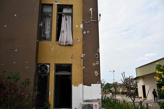 Damage sustained during fighting between Thailand and Cambodia is pictured on the outside of an abandoned scam centre in O'Smach town on the Thai-Cambodian border on March 12, 2026, during a press trip organised by Thailand's Ministry of Foreign Affairs and the Royal Thai Army. Broken computer monitors in bombed-out offices, scattered fake police uniforms, phony hundred dollar bills, Chinese tea tables: these were the vestiges of a frantic escape of suspected cyberscammers fleeing a resort on the Cambodia-Thailand border. (Photo by Lillian SUWANRUMPHA / AFP) / To go with 'THAILAND-CAMBODIA-CONFLICT-CYBERCRIME,FOCUS' by Chayanit ITTHIPONGMAETEE and Sally JENSEN
