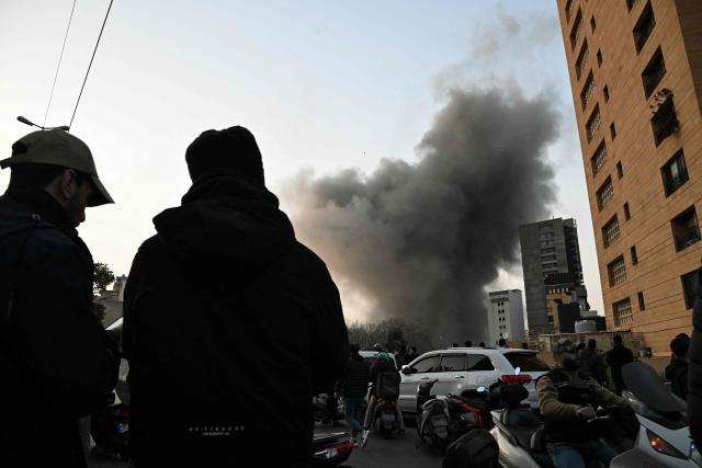 People watch a plume of smoke rising following an Israeli missile strike in the neighbourhood of Bashoura in central Beirut on March 12, 2026. The Israeli military said it had begun a wave of strikes across Beirut on March 12, after it warned residents of a central neighbourhood of the Lebanese capital it would target a building there. (Photo by JOSEPH EID / AFP)