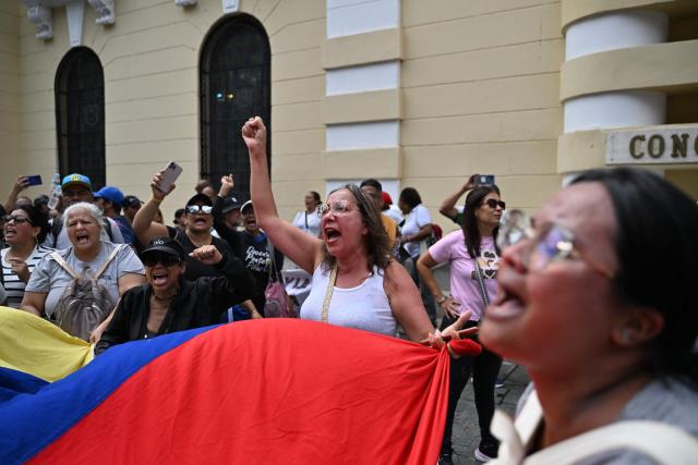 University workers shout slogans as they protest for the rise in salaries and pensions with a Venezuelan national flag outside the National Assembly building in Caracas on March 12, 2026. (Photo by Juan BARRETO / AFP)