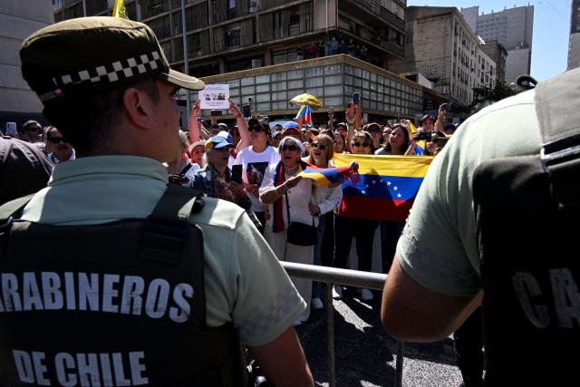 Members of the Venezuelan community wait for the arrival of Venezuelan opposition leader Maria Corina Machado, who is set to receive the key to the city outside the city hall in Santiago on March 12, 2026. Machado travelled to Chile to attend Chile's President Jose Antonio Kast's inauguration. (Photo by RODRIGO ARANGUA / AFP)