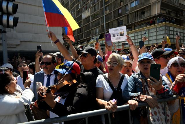 Members of the Venezuelan community wait for the arrival of Venezuelan opposition leader Maria Corina Machado, who is set to receive the key to the city outside the city hall in Santiago on March 12, 2026. Machado travelled to Chile to attend Chile's President Jose Antonio Kast's inauguration. (Photo by RODRIGO ARANGUA / AFP)