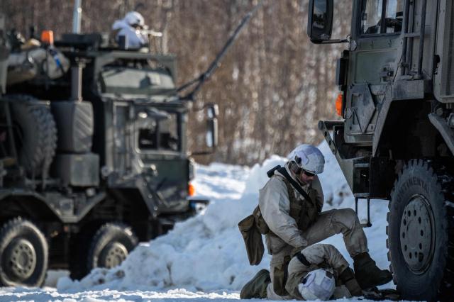 A member of the Norwegian army Combat Support Battalion looks over a wounded comrade, as another one returns fire during an attack simulation on a logistics unit near Setermoen on March 12, 2026, as NATO conducts its Cold Response military exercise. The Norwegian-led winter exercise involves 32.000 troops, 100 aircraft, and 30 warships from 14 nations taking part in high intensity, multi-domain operations in an arctic climate. (Photo by John MACDOUGALL / AFP)