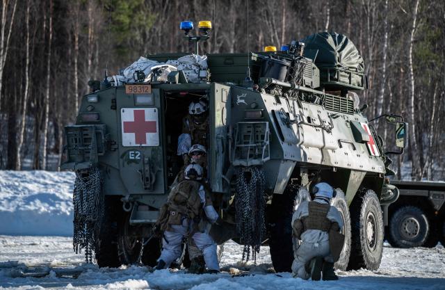 Norwegian army medics drag a wounded comrade from the Norwegian army Combat Support Battalion into a Patria Pasi APC after he was wounded during an attack simulation on a logistics unit near Setermoen on March 12, 2026, as NATO conducts its Cold Response military exercise. The Norwegian-led winter exercise involves 32.000 troops, 100 aircraft, and 30 warships from 14 nations taking part in high intensity, multi-domain operations in an arctic climate. (Photo by John MACDOUGALL / AFP)