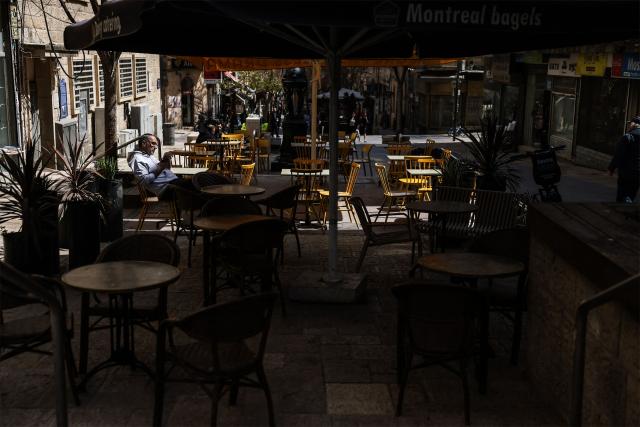 A man sits at a coffee shop along Jaffa Street on day 13 of the US-Israel war on Iran, in west Jerusalem on March 12, 2026. On February 28, Israel and the United States launched strikes on Iran, killing its supreme leader Ayatollah and triggering a war that spread across the Middle East. (Photo by HAZEM BADER / AFP) / 
