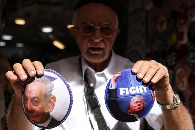 An Israeli vendor displays Jewish skullcaps known as kippah (yarmulke), depicting an image of the US President Donald Trump (R) and Israeli Prime Minister Minister Benjamin Netanyahu, at his shop along Jaffa Street, in west Jerusalem on March 12, 2026. On February 28, Israel and the United States launched strikes on Iran, killing its supreme leader Ayatollah and triggering a war that spread across the Middle East. (Photo by HAZEM BADER / AFP) / 