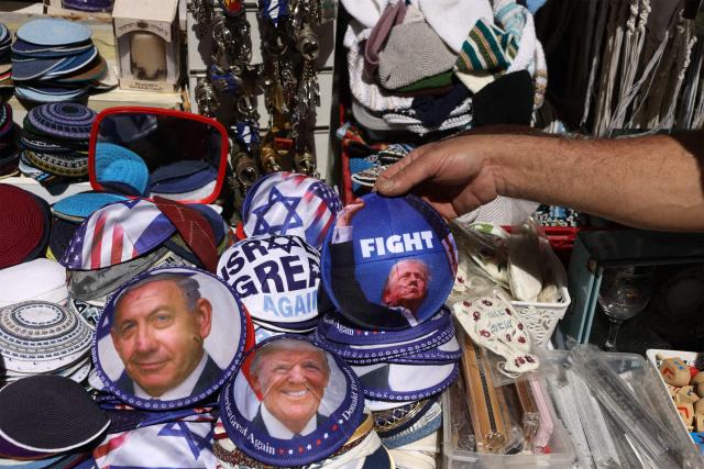 An Israeli vendor displays Jewish skullcaps known as kippah (yarmulke), depicting an image of the US President Donald Trump (R) and Israeli Prime Minister Minister Benjamin Netanyahu, at his shop along Jaffa Street, in west Jerusalem on March 12, 2026. On February 28, Israel and the United States launched strikes on Iran, killing its supreme leader Ayatollah and triggering a war that spread across the Middle East. (Photo by HAZEM BADER / AFP) / 
