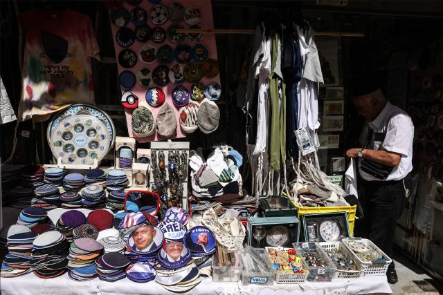 An Israeli vendor displays Jewish skullcaps known as kippah (yarmulke), depicting an image of the US President Donald Trump and Israeli Prime Minister Minister Benjamin Netanyahu, at his shop along Jaffa Street, in west Jerusalem on March 12, 2026. On February 28, Israel and the United States launched strikes on Iran, killing its supreme leader Ayatollah and triggering a war that spread across the Middle East. (Photo by HAZEM BADER / AFP) / 