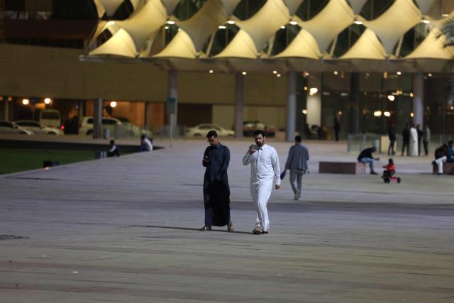 Saudis men walk in the grounds of the King Fahad Library in the Saudi capital Riyadh City on March 12, 2026. The oil-rich gulf has borne the brunt of Iran's attack in response to US-Israel strikes that sparked the Middle East war, with Tehran targeting US assets but also civilian infrastructure, including energy facilities and airports. (Photo by AFP) / 