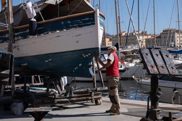 A man repairs a boat in the old harbor Marseille, southern France, on March 12, 2026. (Photo by Elodie CLEMENT / AFP)