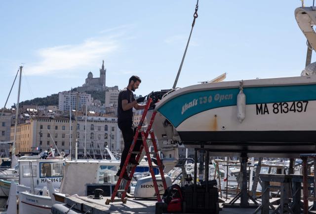 A man repairs a boat in the old harbor Marseille, southern France, on March 12, 2026. (Photo by Elodie CLEMENT / AFP)