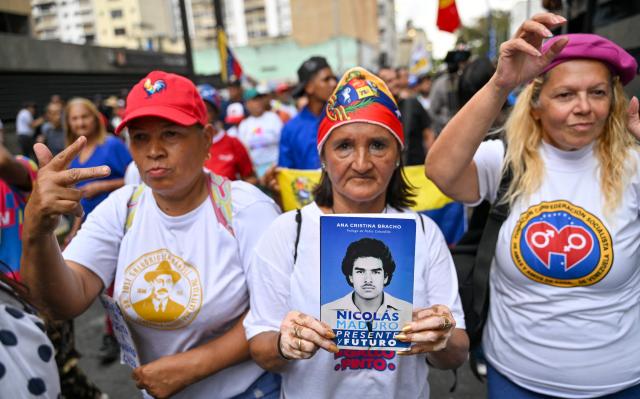 Supporters of Venezuela’s ousted president Nicolas Maduro, take part in a march demanding his release by the US, with a book called "Nicolas Maduro, present and future" in Caracas on March 12, 2026. (Photo by Juan BARRETO / AFP)