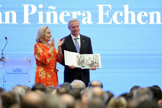 Chile's new President Jose Antonio Kast receives a photography book with images taken by photographer Marcelo Segura from Cecilia Morel, widow of former Chilean president Sebastian Pinera, during the inauguration of the Sebastian Pinera Chair at the Universidad del Desarrollo in Santiago on March 12, 2026. (Photo by Javier TORRES / AFP)