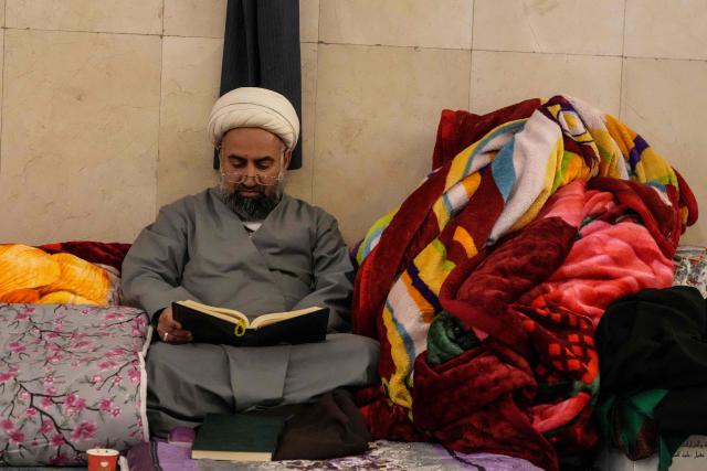 A Shia Muslim faithful recites from a copy of the Koran, Islam's holy book, as he participates in the ritual of Itikaf, or spiritual retreat, at the Kufa Mosque, taking advantage of the days and nights of Laylat al-Qadr, or the Night of Destiny, one of the holiest nights during the fasting month of Ramadan, to pray in the holy city of Kufa, south of the Iraqi capital Baghdad on March 12, 2026. (Photo by AFP)