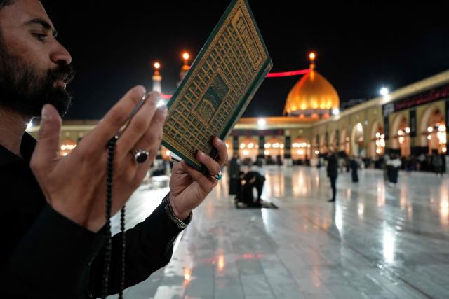 A Shia Muslim faithful recites from a copy of the Koran, Islam's holy book, as he participates in the ritual of Itikaf, or spiritual retreat, at the Kufa Mosque, taking advantage of the days and nights of Laylat al-Qadr, or the Night of Destiny, one of the holiest nights during the fasting month of Ramadan, to pray in the holy city of Kufa, south of the Iraqi capital Baghdad on March 12, 2026. (Photo by Qassem al-KAABI / AFP)