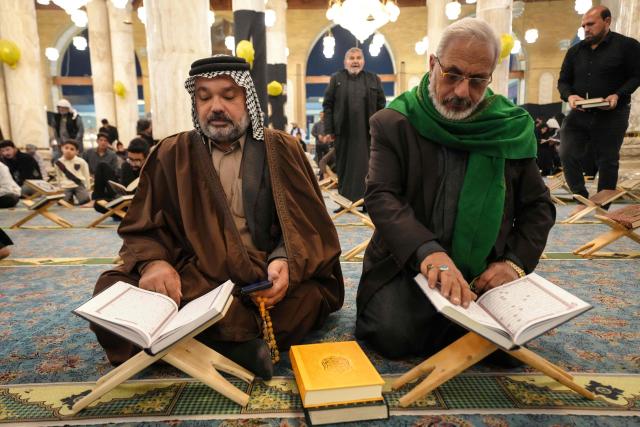 Shia Muslim faithful recite from a copy of the Koran, Islam's holy book, participates in the ritual of Itikaf, or spiritual retreat, at the Kufa Mosque, taking advantage of the days and nights of Laylat al-Qadr, or the Night of Destiny, one of the holiest nights during the fasting month of Ramadan, to pray in the holy city of Kufa, south of the Iraqi capital Baghdad on March 12, 2026. (Photo by AFP)